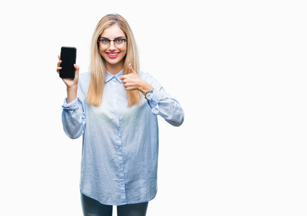 Genç güzel sarışın iş kadın gösteren ekran smartphone üzerinde izole arka ok işareti, başparmak ile parmak, mükemmel işareti yapıyor kocaman bir gülümseme ile mutlu - Fotoğraf, Görsel