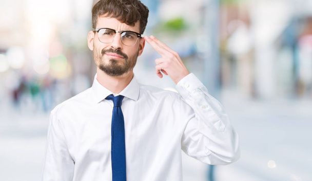 Young handsome business man wearing glasses over isolated background Shooting and killing oneself pointing hand and fingers to head, suicide gesture. - Photo, Image
