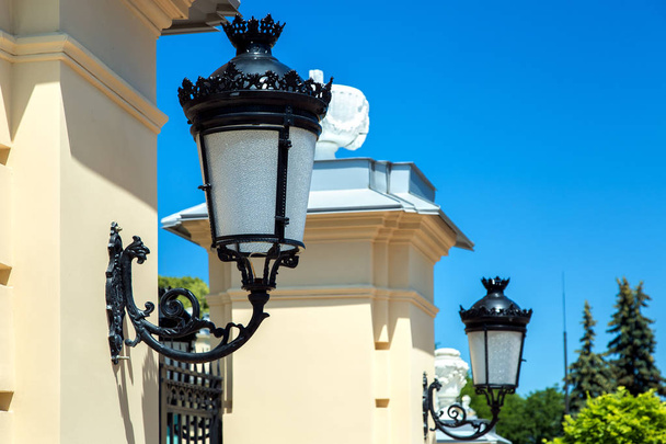 Black wrought iron lamps mounted on the tower at the entrance to the gate. - Photo, Image