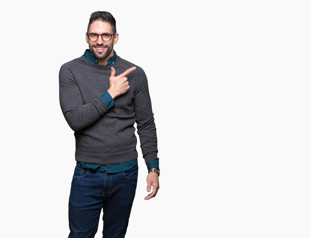 Young handsome man wearing glasses over isolated background cheerful with a smile of face pointing with hand and finger up to the side with happy and natural expression on face - Photo, Image