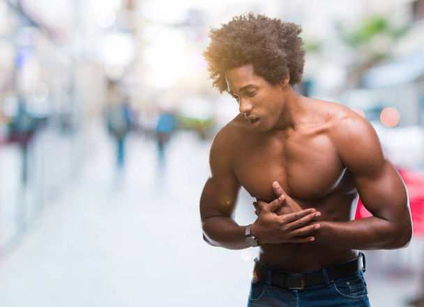 Afro Αμερικανός shirtless άνδρας παρουσιάζει το γυμνό σώμα πάνω από το απομονωμένο φόντο με το χέρι στο στομάχι, γιατί δυσπεψία, επώδυνη ασθένεια αδιαθεσία. Πονούν έννοια. - Φωτογραφία, εικόνα