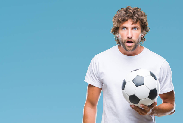 Hispánský aristokratickým model drží fotbal fotbalový míč nad izolované pozadí strach v šoku s tváří překvapení, strach a vzrušený výraz strachu - Fotografie, Obrázek