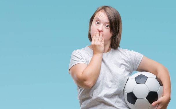 Young adult woman with down syndrome holding soccer football ball, covering mouth with hand  - 写真・画像