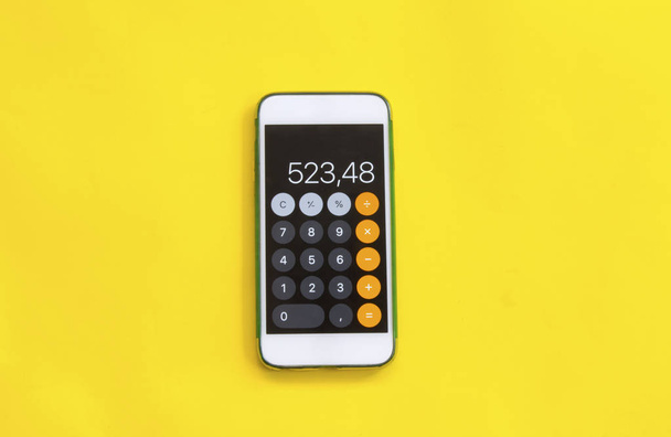 teléfono inteligente con calculadora sobre fondo amarillo
 - Foto, imagen