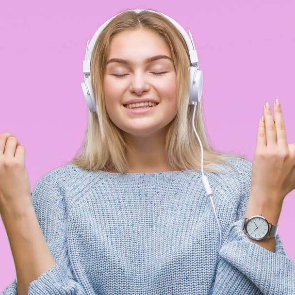 Mujer caucásica joven escuchando música con auriculares sobre un fondo aislado celebrando loco y loco por el éxito con los brazos levantados y los ojos cerrados gritando emocionados. Concepto ganador
 - Foto, imagen