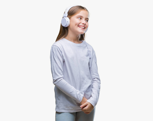 Mooi meisje koptelefoon luisteren naar muziek op geïsoleerde achtergrond op zoek weg aan kant met glimlach op gezicht, natuurlijke uitdrukking dragen. Lachen vertrouwen. - Foto, afbeelding