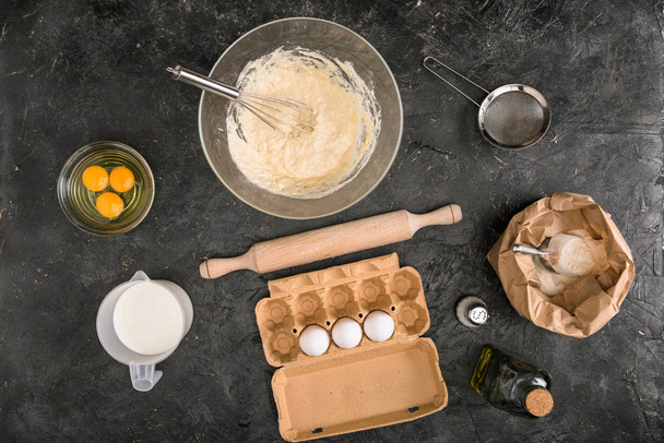 vista superior de la masa, ingredientes y utensilios de cocina sobre fondo gris
 - Foto, Imagen