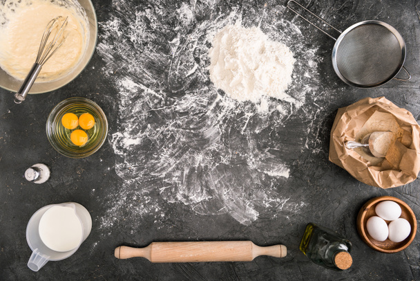 top view of dough, ingredients and cooking utensils on grey background - Fotó, kép