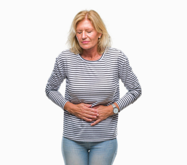 Middle age blonde woman over isolated background with hand on stomach because indigestion, painful illness feeling unwell. Ache concept. - Photo, Image