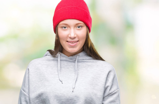 Молодая кавказская красивая женщина в шерстяной шапке на изолированном фоне со счастливой и прохладной улыбкой на лице. Счастливчик
. - Фото, изображение