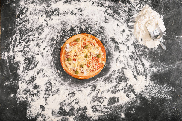 小麦粉と灰色の背景に未調理ピザのトップ ビュー - 写真・画像