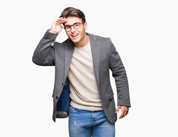 Giovane uomo d'affari indossa occhiali su sfondo isolato molto felice e sorridente guardando lontano con mano sopra la testa. Concetto di ricerca
. - Foto, immagini
