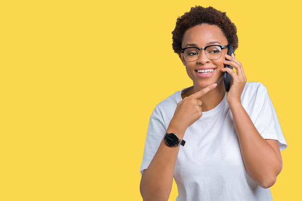 Jeune femme afro-américaine parlant au téléphone sur fond isolé très heureux pointant avec la main et le doigt
 - Photo, image