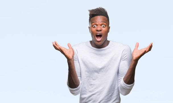 Young african american man over isolated background celebrating crazy and amazed for success with arms raised and open eyes screaming excited. Winner concept - Photo, Image