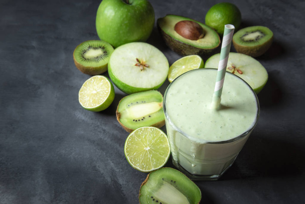 Fresh healthy smoothie in a glass and green fruits on a greyish kitchen table. Dieting context. Vegetarian food. Detox concept. Copy space. - Foto, imagen