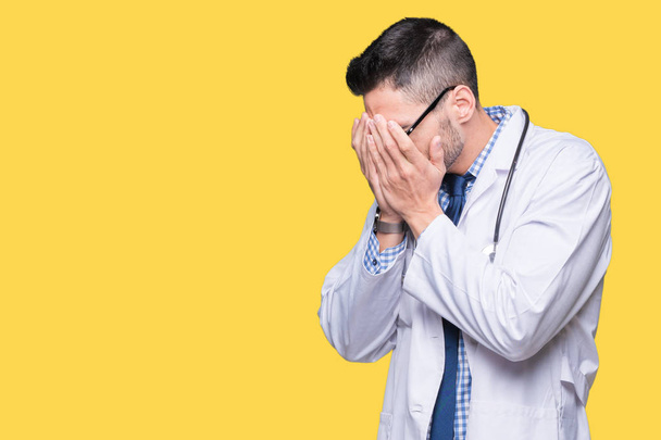 Pohledný mladý lékař muž nad izolované pozadí se smutným výrazem pokrývající obličej rukama a plakat. Koncept deprese. - Fotografie, Obrázek