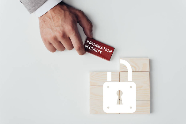 partial view of man holding brick with 'information security' lettering over wooden blocks with lock icon isolated on white - Photo, Image