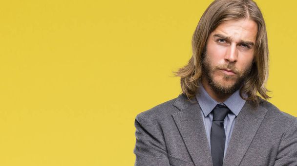 Young handsome business man with long hair over isolated background skeptic and nervous, disapproving expression on face with crossed arms. Negative person. - Foto, imagen