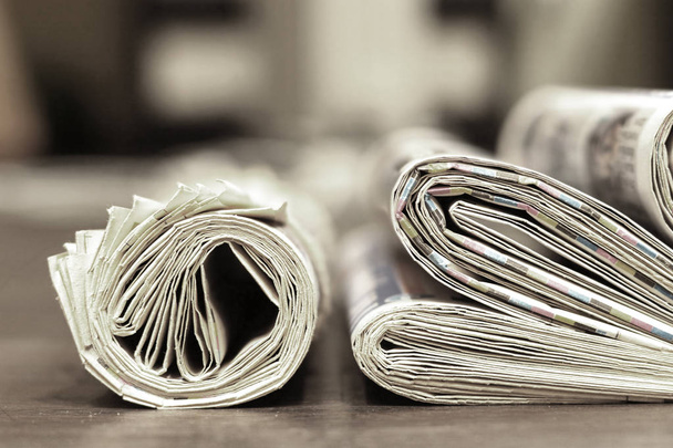 Складные и свернутые газеты, сложенные в кучу на деревянном столе, вид сбоку
   - Фото, изображение