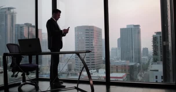 Biznesmen przy użyciu smartfona w biurze drapacz chmur - Materiał filmowy, wideo