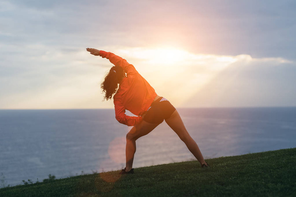 Sporty woman stretching and exercising outdoor at sunrise. Healthy lifestyle and sport concept. - Foto, Imagem