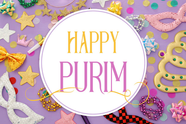 Purim celebration concept (jewish carnival holiday) with masks and colorful party accessories over pink, purple wooden background. Top view - Foto, immagini