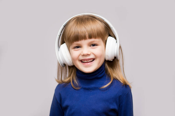 Happy smiling child enjoys listens to music in headphones over white background - Foto, imagen