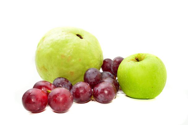 Verse guava en groene appel met rode druiven geïsoleerd op witte achtergrond - Foto, afbeelding