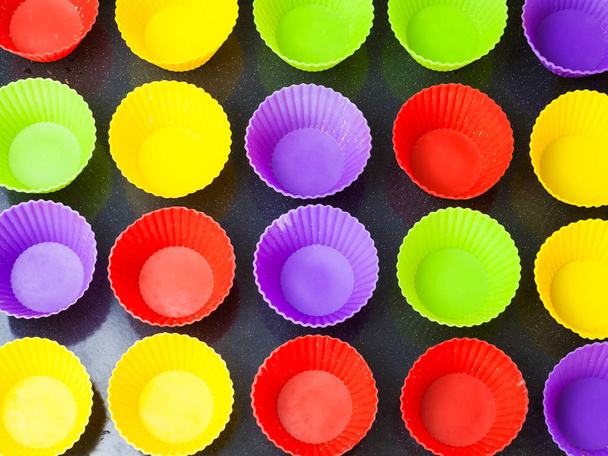vue de dessus de nombreux moules en silicone multicolores vides pour muffins sur plaque de cuisson
 - Photo, image
