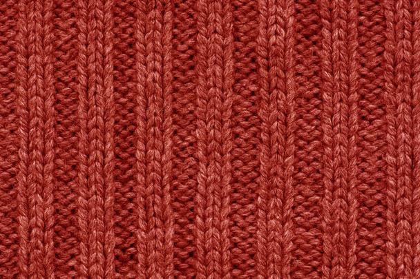 Gebreide patroon. Patroon stof gemaakt van wol. Achtergrond, kopie ruimte. Handgemaakte trui patroon, gebreid van wol patroon, rode achtergrond - Foto, afbeelding