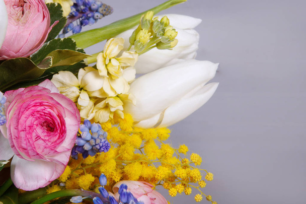 Ramo de arreglos florales de ranúnculo, jacinto, tulipán, mimosa sobre un fondo de madera gris. Para decoración, diseño web. De cerca.
. - Foto, Imagen