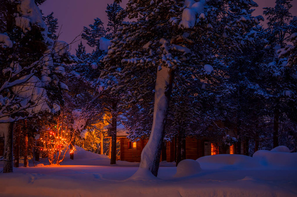 Finnish Lapland. Cottage in the night winter forest and Christmas garland. A lot of snow - Foto, imagen