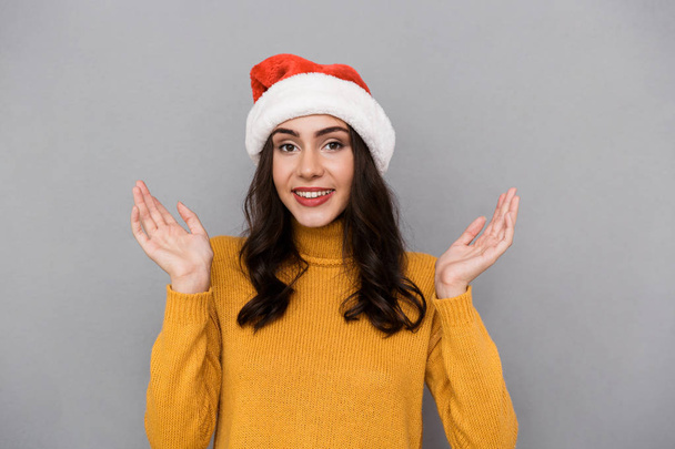 Portrait of positive woman wearing Santa Claus red hat smiling and having fun isolated over gray background - Fotografie, Obrázek