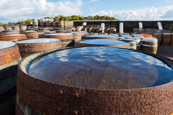 Barriles y barriles de madera viejos están bajo cielo abierto madurando whisky escocés de malta simple en la destilería de whisky en Escocia
. - Foto, Imagen