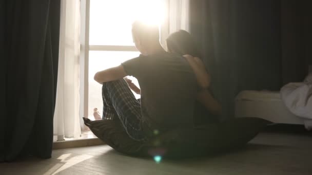 Romantik Çift pijama sabah yere oturma. Güzel genç yetişkin beyaz kadın ve güneş ışığı içinde belgili tanımlık pencere önünde oturan adam odaya döktü - Video, Çekim