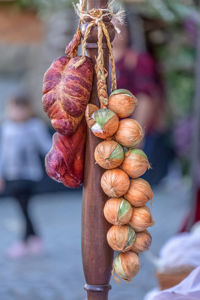 View of wooden pole with onions and dried meat in traditional market... - Photo, Image