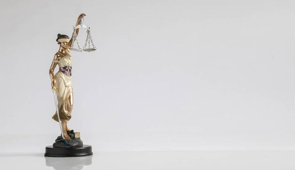 Фігура богині справедливості з лускою в руці стоїть на плоскій поверхні на білому тлі. Концепція є обґрунтованим принципом права
. - Фото, зображення