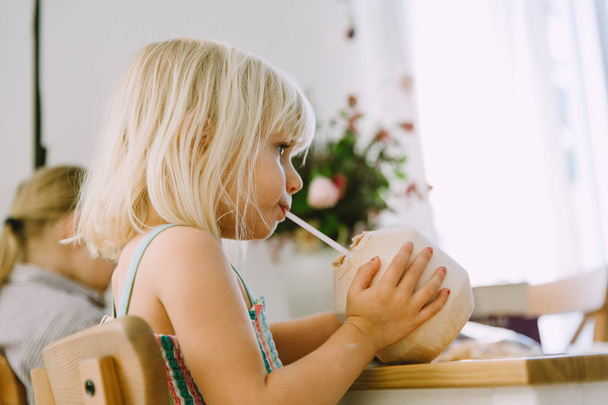 αξιολάτρευτο κοριτσάκι πίνουν γάλα καρύδας στο σπίτι  - Φωτογραφία, εικόνα