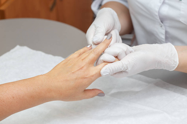 Massage therapist in latex gloves massaging hands of a woman in a beauty salon, closeup - Foto, Bild