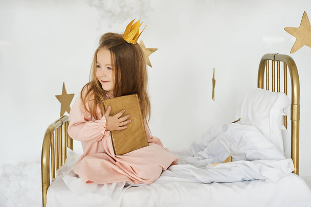 Little princess with a magic wand on  bed in a cloud on a white background - Foto, Imagen