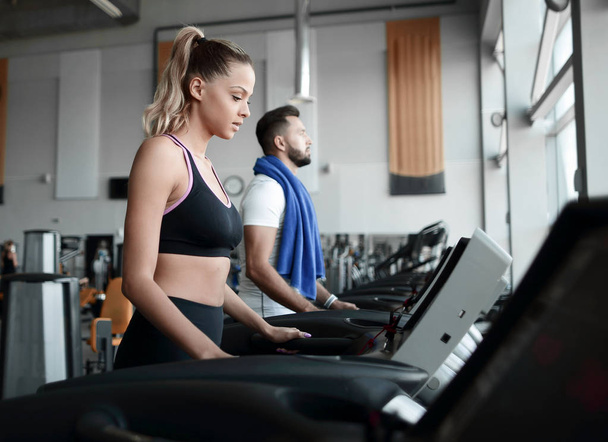 beautiful sports people work on the treadmill in the gym - Фото, изображение