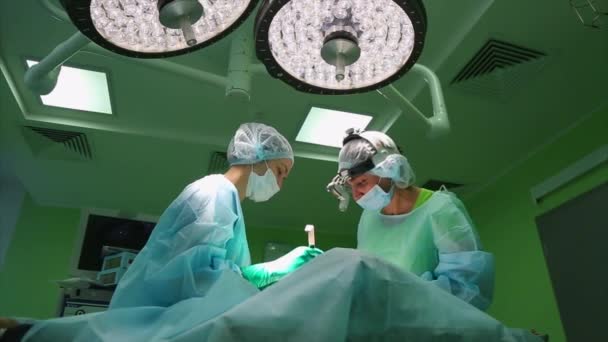 Chirurg und Chirurgenteam führen im Operationssaal des Krankenhauses Schönheitsoperationen an den Brüsten durch. Brustvergrößerung. Mammoplastik. Brustvergrößerung. Detail der Operation. - Filmmaterial, Video