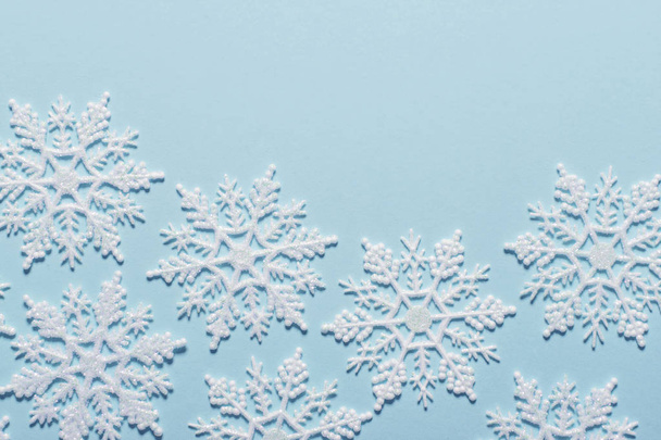 White glitter snowflake composition on a pastel blue background - Фото, изображение
