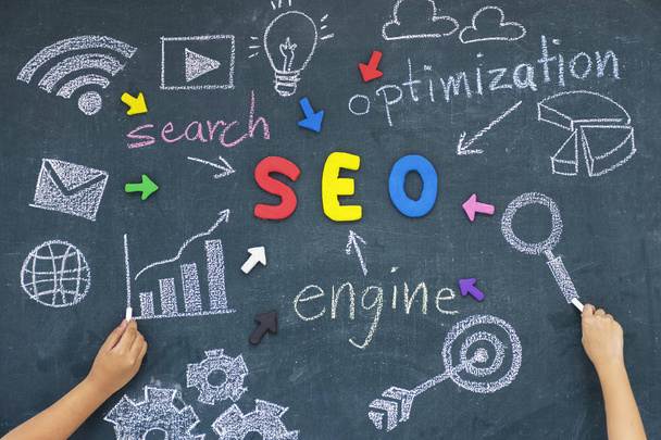 SEO, Search Engine Optimization ranking concept,with arrows pointing to alphabets abbreviation SEO at the center of cement wall chalkboard and Computer Symbols,the idea of promote traffic to website. - Photo, image