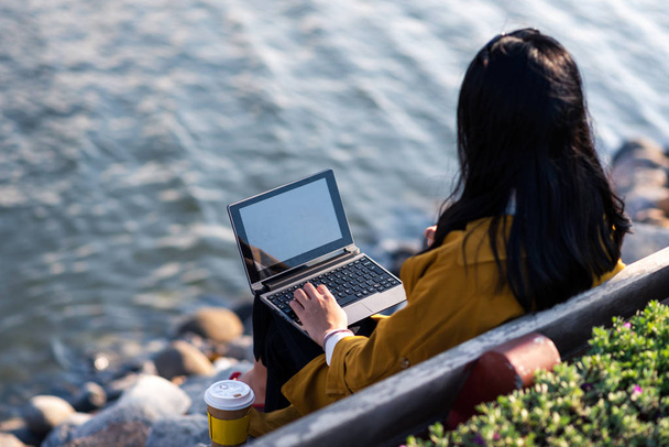 Lány dolgozik a laptop kívül a tó partján - Fotó, kép