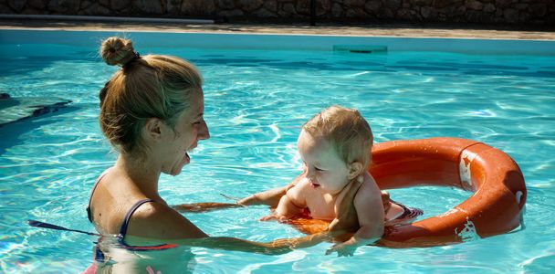 Moeder en baby met zwem ring in zwembad - Foto, afbeelding