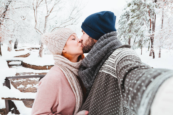 Young couple taking a selfie in a park on a snowy day - Fotoğraf, Görsel