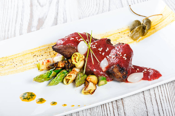 Fried meat steak with bbq sauce, asparagus and herbs on plate on wooden background. Hot Meat Dishes. Top view - 写真・画像