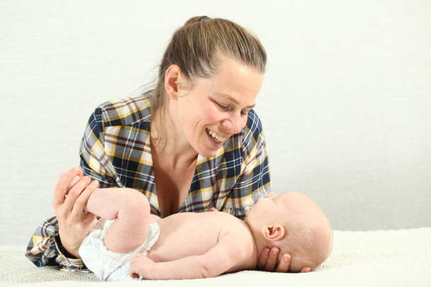 mother with a newborn baby changes the diaper to the baby. - Photo, Image