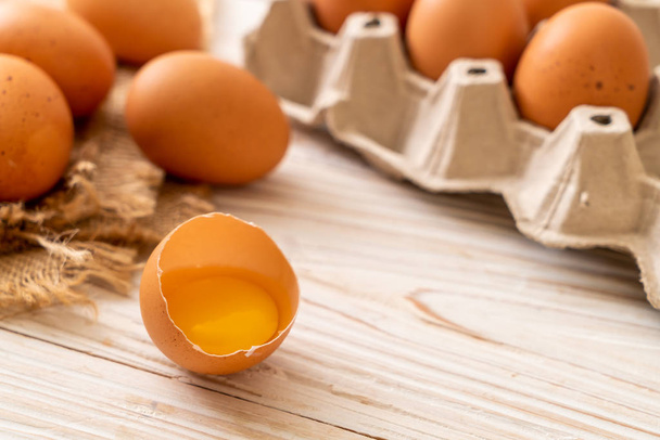 Brown eggs on wooden table with one broken and egg yolk - Φωτογραφία, εικόνα